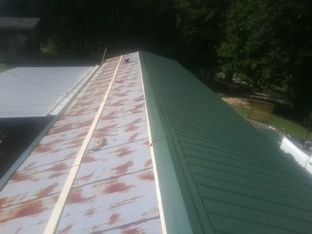 Old rusted panels beside newly installed green metal roofing — Wind Damage Roof Repair by Roofing Brothers in Excelsior Springs