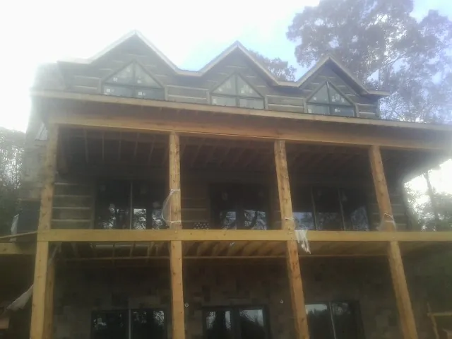 Dormers and porch framing on a large log home under construction — Roof Coating work by our crew in Excelsior Springs