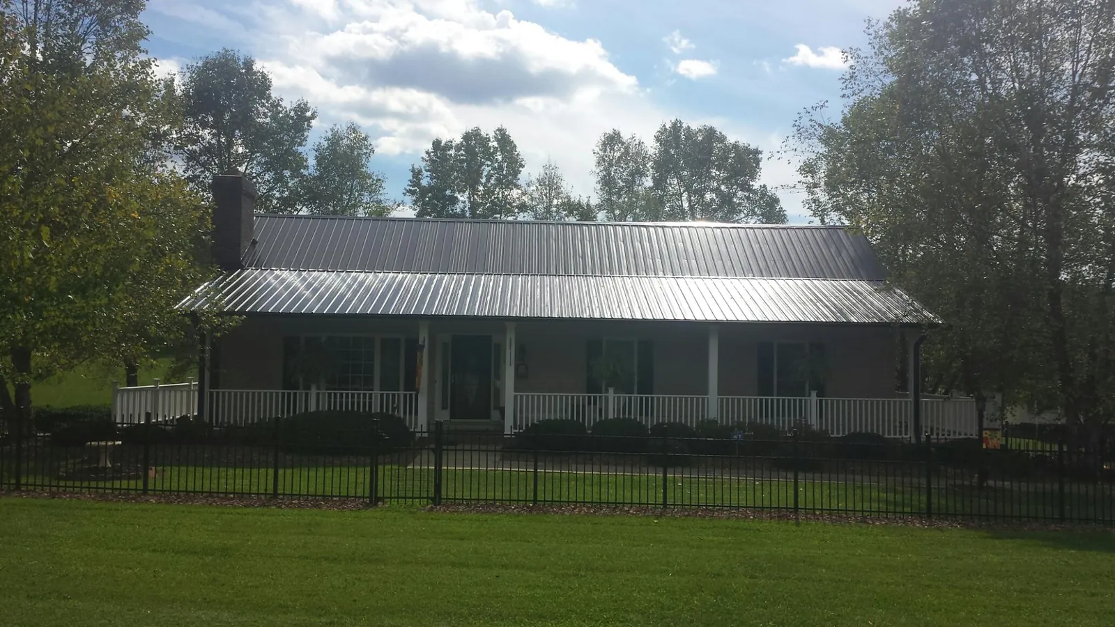 Gray metal roof on a brick ranch with a full width front porch — Gutter Guard Installation work by our crew in Excelsior Springs