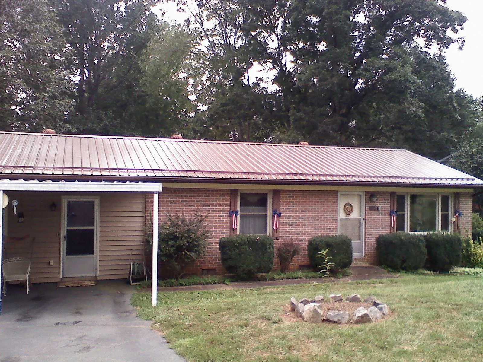 Bronze metal roof and carport on a brick ranch home — Roof Repair work by our crew in Excelsior Springs