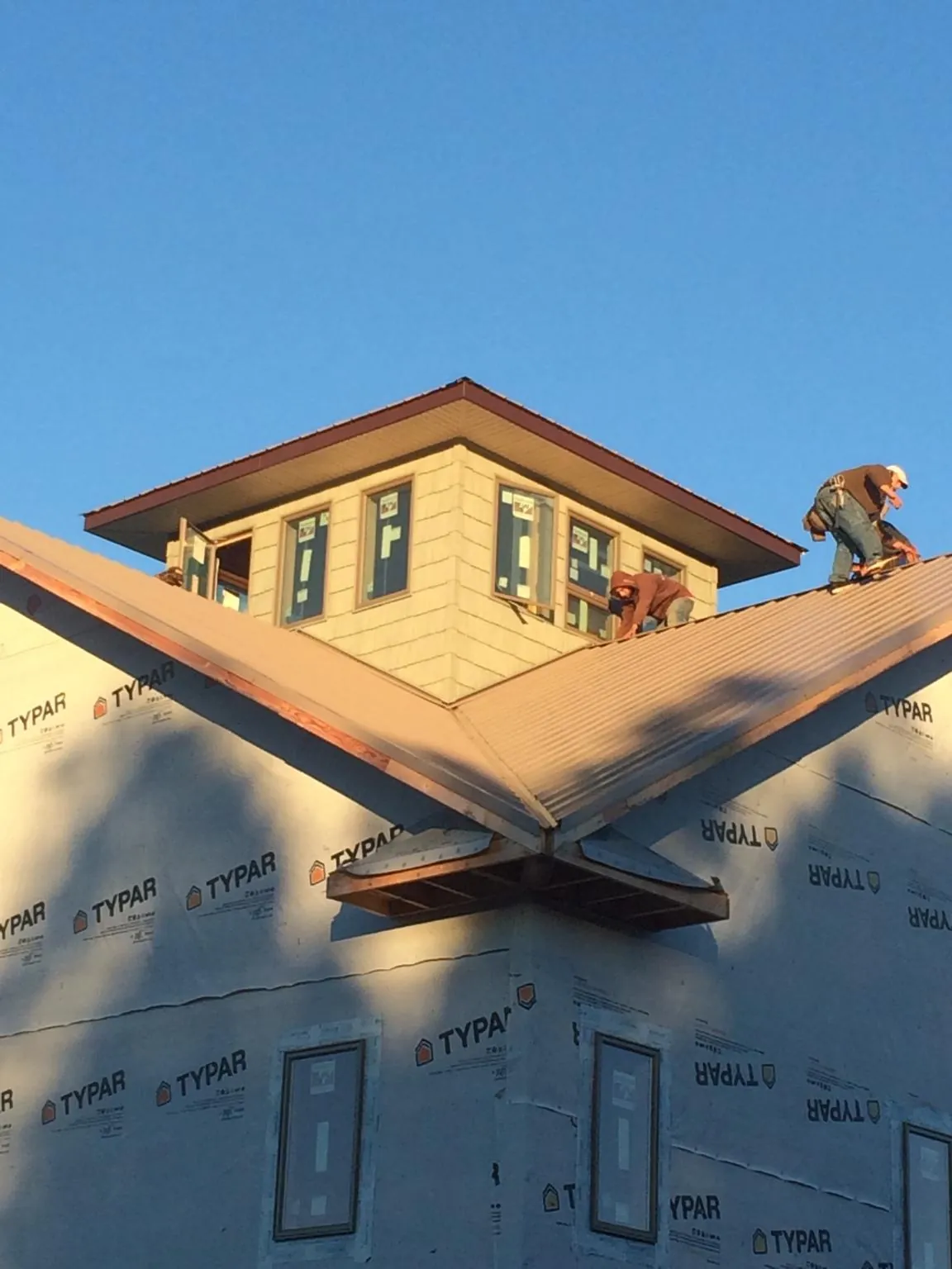 Roofers working around a rooftop cupola on a new metal roof at sunset — Roof Waterproofing in Excelsior Springs by Roofing Brothers